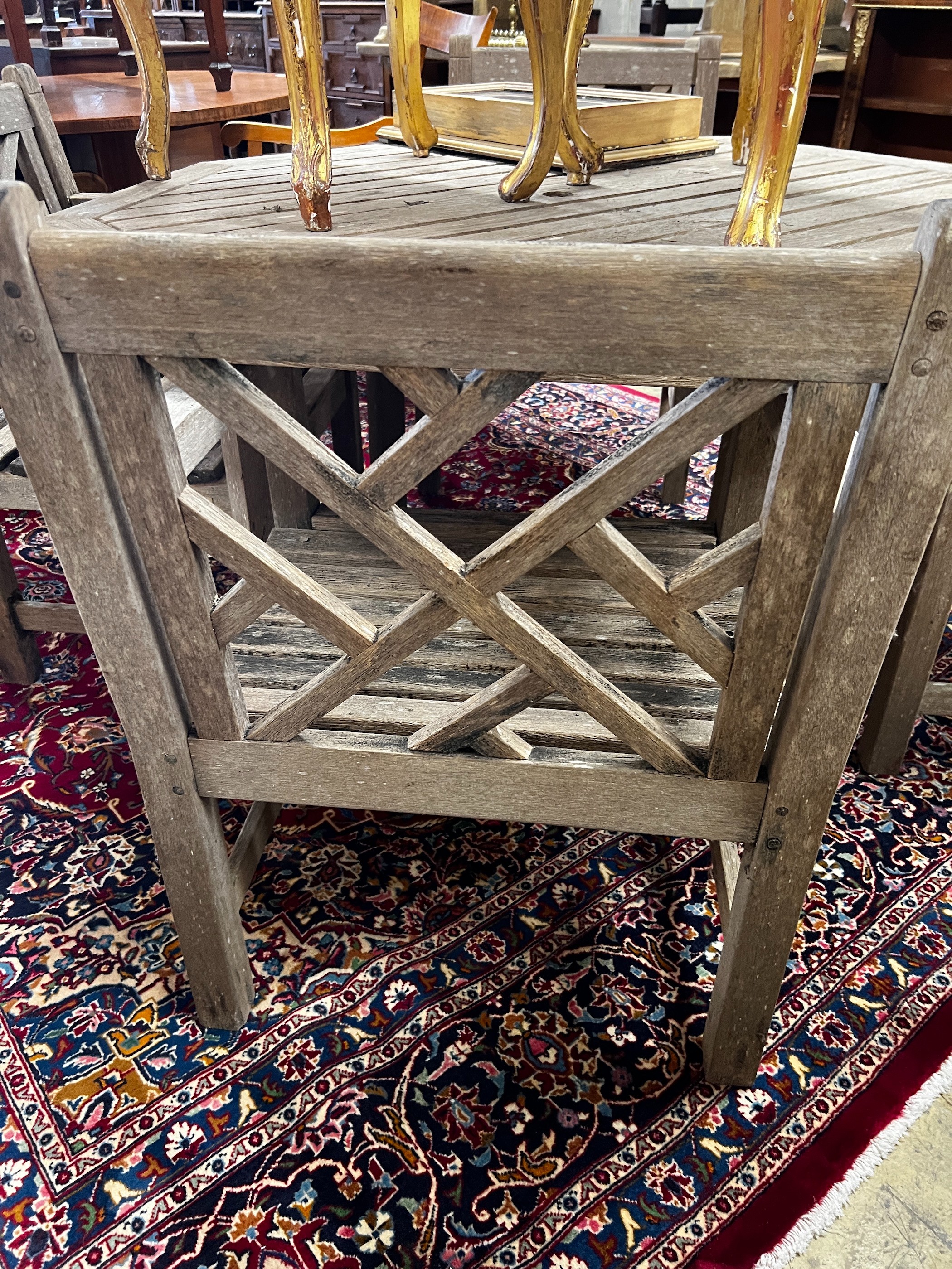 An octagonal weathered teak garden table, length 126cm, height 69cm and four teak elbow chairs